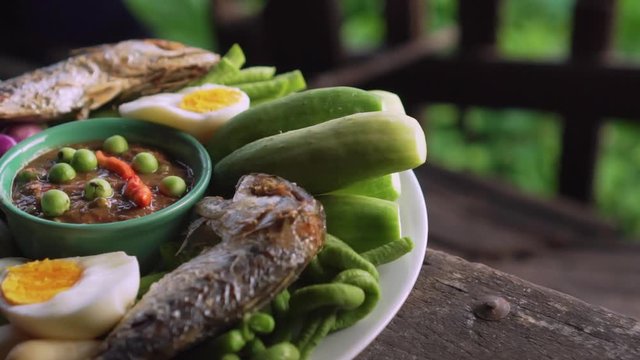 Set plate of fried mackerel with shrimp paste sauce and vegetables. Thai dish. slow motion. slide shot.