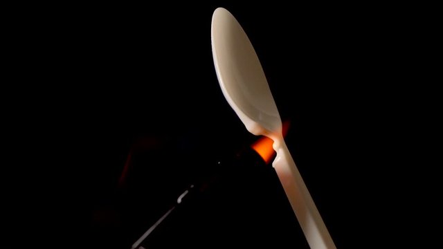 Torch melts plastic spoon on black background. Concept say no to plastic.