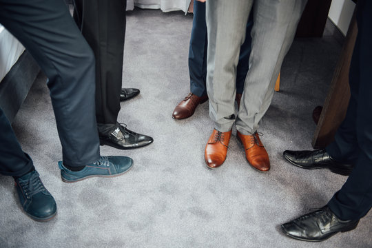 Groom and groomsmen men in blue suits standing in group with closeup of shoes and feet