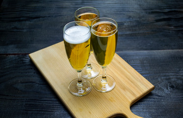 three glasses with beer on a wooden tray