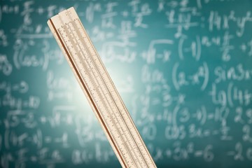 Wooden ruler on the background of a blackboard with formulas