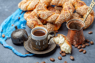 Turkish black coffee served in traditional ceramic cup with sesame bagel, selective focus.