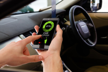 Charging Electric car Looking at App On Mobile Phone. Close up of smartphone screen. Hand holding smart device. Mobile application for eco transportation