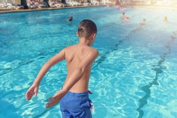 Boy having fun on summer vacation. He prepearing to make high jump into swimming pool.