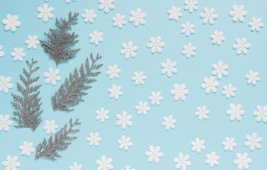 Fototapeta na wymiar Holiday pastel background, white snowflakes and thuja twigs on a gentle blue background ,flat lay, top view