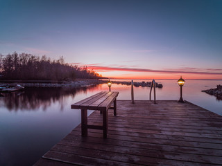 Naklejka premium Wooden pier with a bench and a lantern on the shore of Lake Ladoga