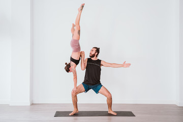 Fototapeta na wymiar young couple Couple practicing acro yoga in white studio or gym. Healthy lifestyle