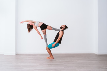 young couple Couple practicing acro yoga in white studio or gym. Healthy lifestyle