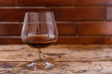 Glass of strong cognac drink on wooden background.