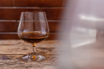 Glass of strong cognac drink on wooden background.