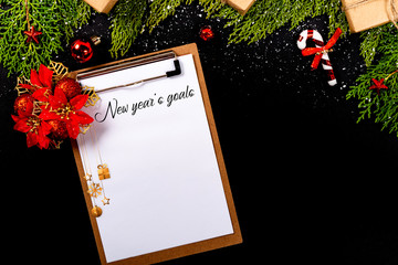 Christmas composition. Girlanda with Christmas ornaments and gifts on black background and blank notepad. Christmas, winter, new year concept. New year´s goals © Julio Ricco