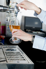 Two hands of a waiter filling the glasses of beer