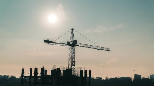 Timelapse of a working construction crane on a background of sunset. Building