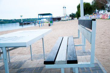 мWhite table and bench on the beach. River or sea.