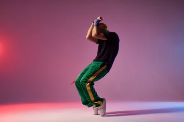 Gordijnen Moderne hiphopdanser bevroren in film, op zijn tenen staan, hoofd met handen bedekken, danselement uitdrukken, oefenen in dansstudio, vol energie breakdancer © alfa27