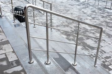 Stainless chrome metal fencing and handrail with stairs leading down in the sreet near the shopping center.