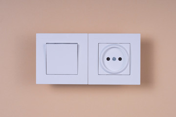 White switch and socket on a beige background.