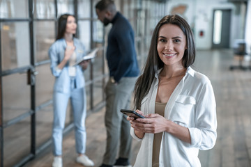 Important business talk. Beautiful young asian woman talking on the mobile phone and smiling while standing in modern office