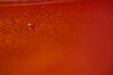 Air bubble in orange drink with glitter closeup in magnification isolated.
