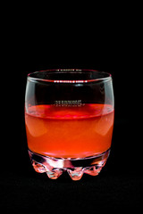 Glitter orange drink in a glass transparent glass isolated on black background close-up
