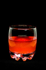 Glitter orange drink in a glass transparent glass isolated on black background close-up