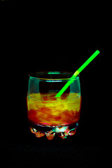 Glitter drink with a cocktail tube close-up isolated on a black background