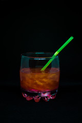 Glitter drink with a cocktail tube close-up isolated on a black background