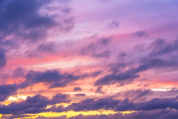 Clouds of different tiers in warm tones of sunset with the sun.