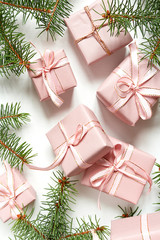 Christmas flat lay. Holiday gifts in boxes in pink packaging and fir branches on a white background with copy space, top view.