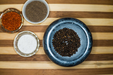 Spices red ground pepper, black ground pepper, salt, peas and peas in a pepper mill on a wooden shelf close-up
