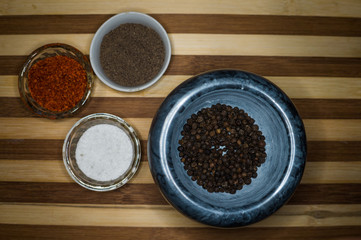 Spices red ground pepper, black ground pepper, salt, peas and peas in a pepper mill on a wooden shelf close-up