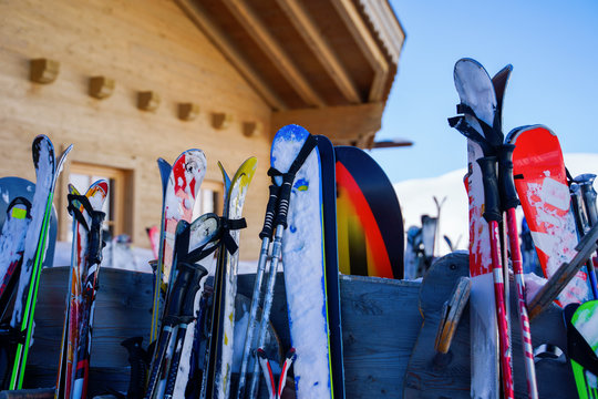 Image of multi-colored skis and snowboards in snow at winter resort in afternoon.