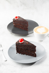 A slice of delicious chocolate cake with cherry on top on marble background. Piece of Cake on a Plate. Sweet food. Sweet dessert. Close up. Cafe menu. vertical photo.