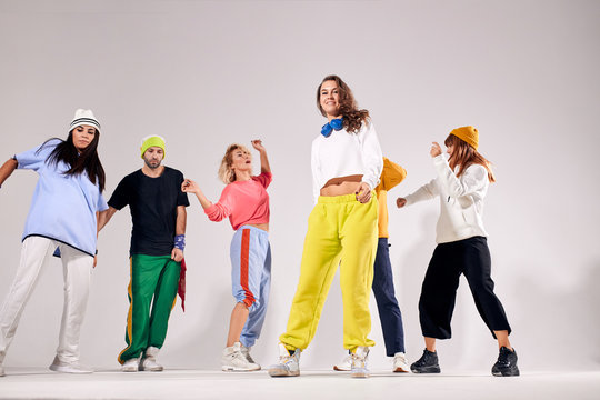 Cool group of young dancers performing on dance school studio, enjoying dance party, having perfect time by training on white floor, isolated photo, indoor shot