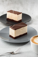 Piece of cake with souffle Bird's milk , biscuit, mousse and dark chocolate on a dark plate, white souffle cake. Menu for bakery. cafe menu. Delicious and sweet dessert at cafe restaurant.Vertical