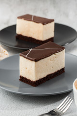 Piece of cake with souffle Bird's milk , biscuit, mousse and dark chocolate on a dark plate, white souffle cake. Menu for bakery. cafe menu. Delicious and sweet dessert at cafe restaurant.Vertical