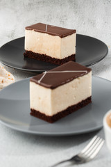 Piece of cake with souffle Bird's milk , biscuit, mousse and dark chocolate on a dark plate, white souffle cake. Menu for bakery. cafe menu. Delicious and sweet dessert at cafe restaurant.Vertical
