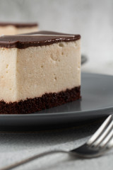 Piece of cake with souffle Bird's milk , biscuit, mousse and dark chocolate on a dark plate, white souffle cake. Menu for bakery. cafe menu. Delicious and sweet dessert at cafe restaurant.Vertical