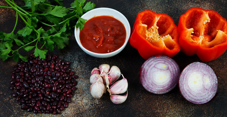 The ingredients for making lobio lie on a concrete table. Top view. Traditional Caucasian dish of red beans vegetables and tomatoes.