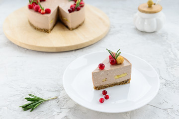 Slice of raw cheesecake with cocoa, banana and berries on a white plate. Gluten free, vegetarian food.