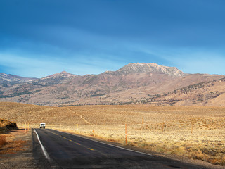 Camper driving an RV down a road in the Sierra Nevada mountains in late autumn