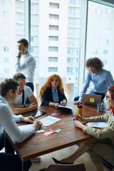 Caucasian creative colleaguew work together, discuss new issues of work, business team. Modern office with panoramic view on city background