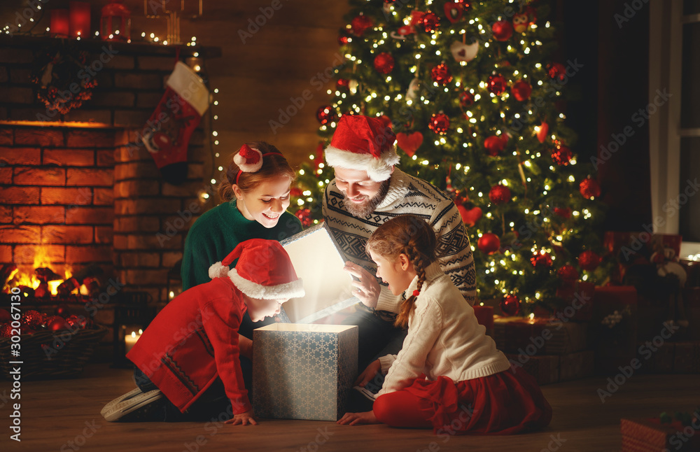 Canvas Prints merry christmas! happy family mother father and children with magic gift near tree at home.