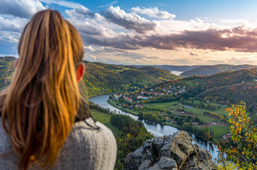 Beautiful girl enjoying life and watching the river, mountains and hills during sunset on the...