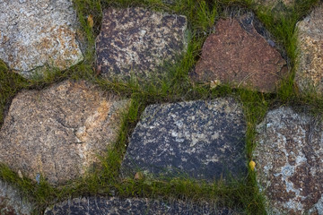 Decorative walkway of texture stone from the Rock. many stones with heterogeneous shapes and grass between the seams