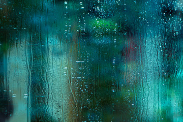 Glass with dripping water and blue green blurs 