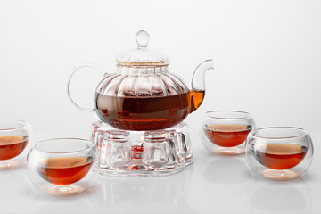 glass teapot on glass stand heated by candle on white background, black tea in glass teapot...