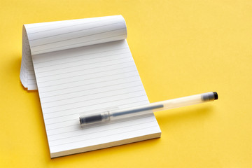 Top view of blank open notebook page with lines and transparent minimalistic fineliner pen on yellow background with copy space. For use as mock up.