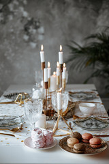 Stylish table served for Christmas dinner in living room. Decor in gold tones