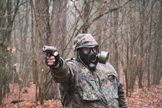 A military man in a gas mask and with a gun aims at the target